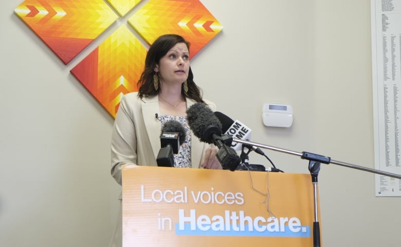 Vicki Mowat stands on a podium inside her Saskatoon office