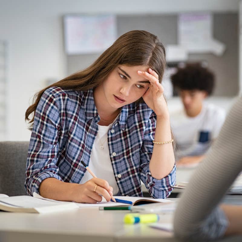 Worried young woman with hand on head feeling tired while studying at school